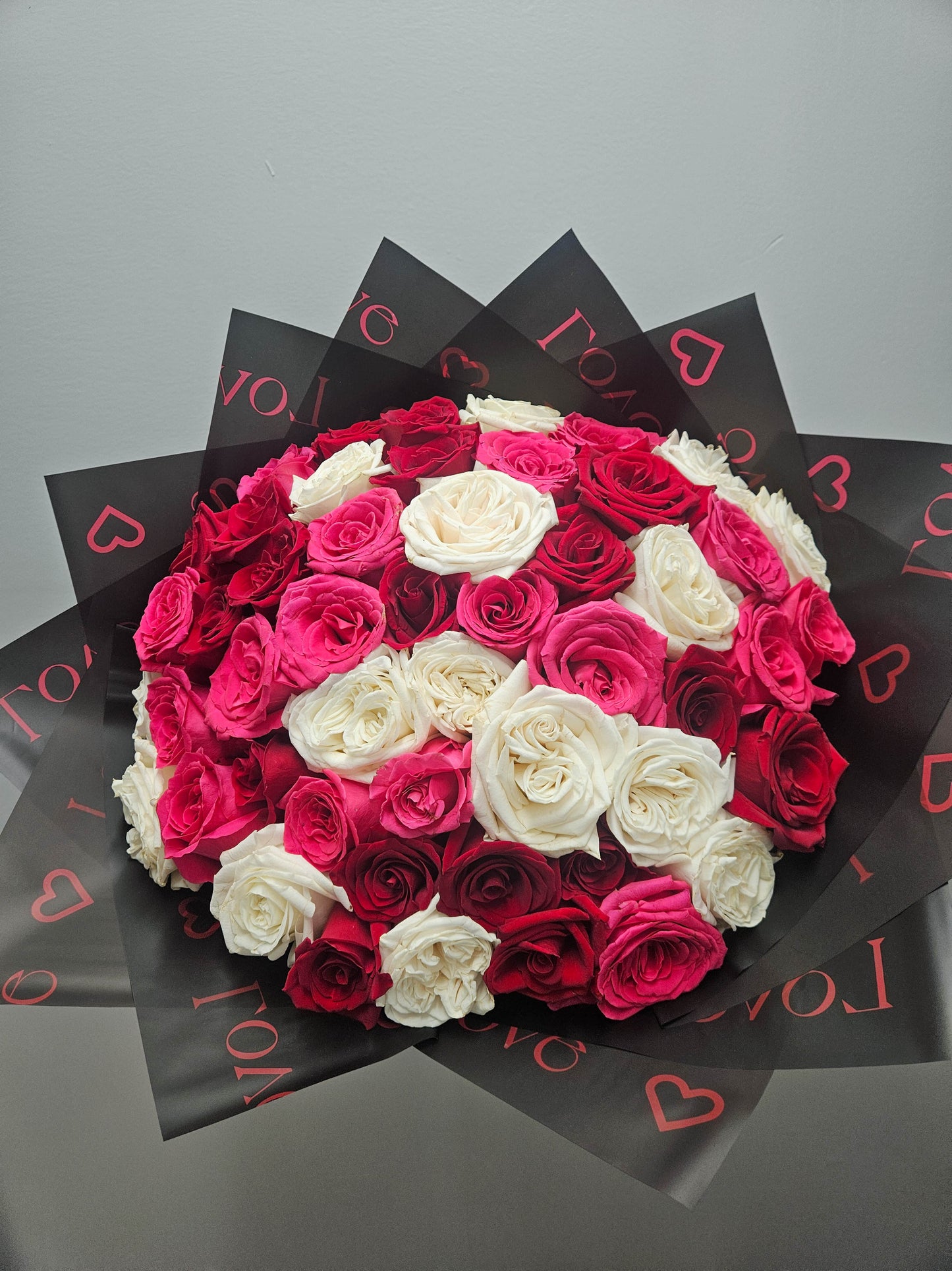 Bouquet of red, pink, and white roses on a gray background