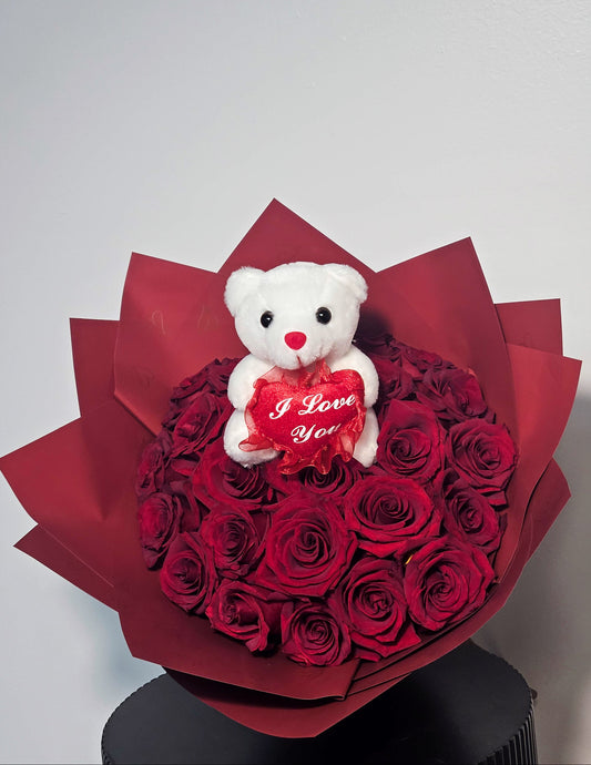 Bouquet of red roses with a white teddy bear holding a 'I Love You' heart on a white background